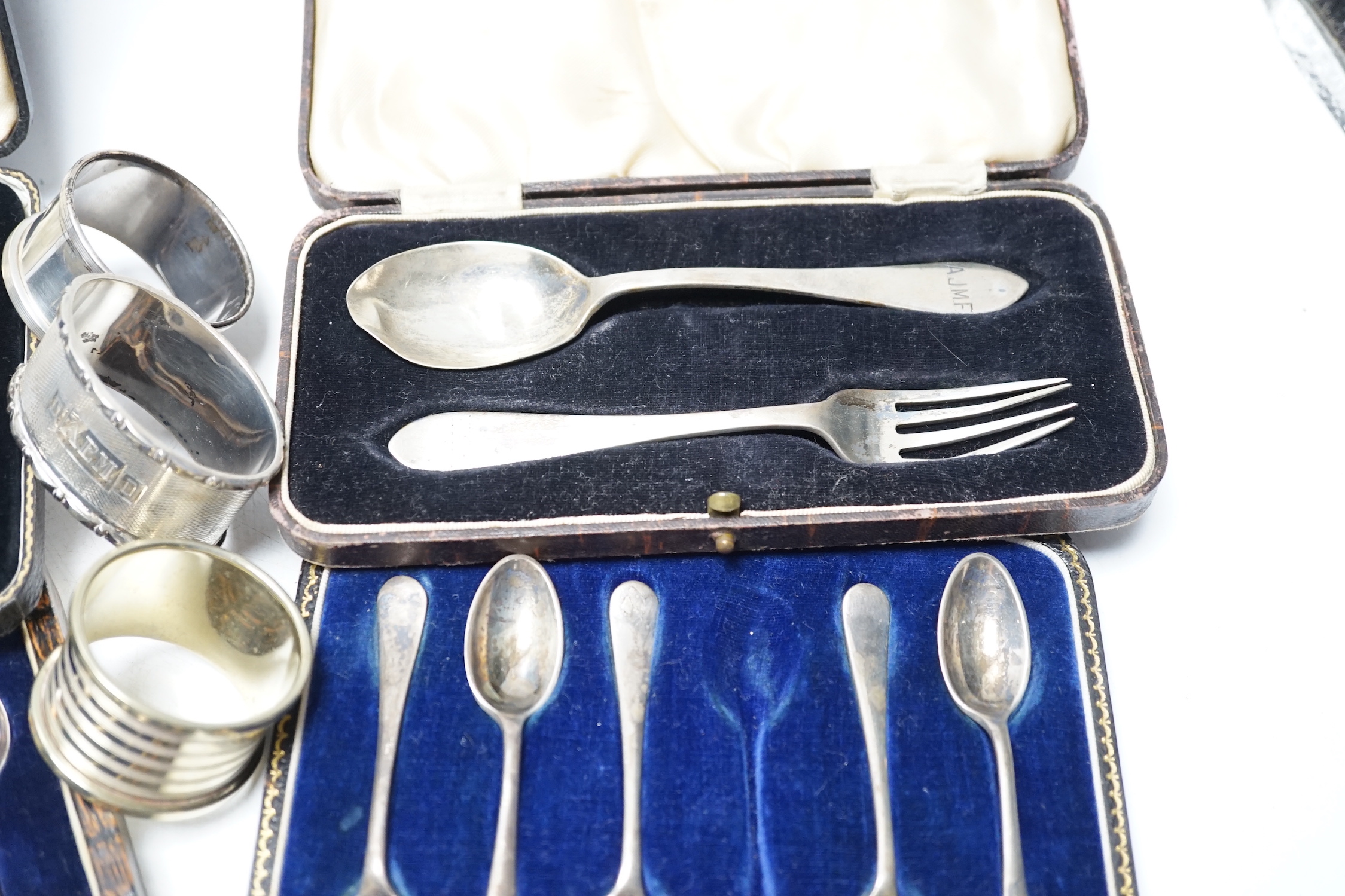 Four various silver serviette rings and a plated napkin ring, two small silver dishes, three various boxed sets of silver flatware and one part set of silver flatware.